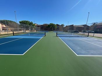 a tennis court with blue and green turf and a fence